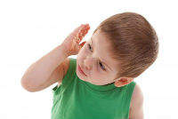 παιδί με πράσινο κοντομάνικο που υψώνει το χέρι κοντά στο αυτί σαν να το ενοχλεί