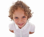 χαμογελαστό παιδί 7 χρονών περίπου με μπούκλες στα μαλλιά και άσπρο κοντομάνικο